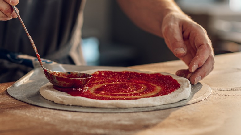 Spreading tomato sauce on pizza