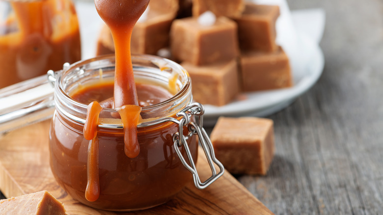 Caramel sauce in a jar next to caramel cubes