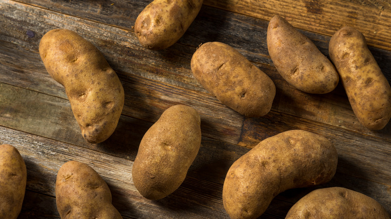 whole Russet potatoes on wooden table