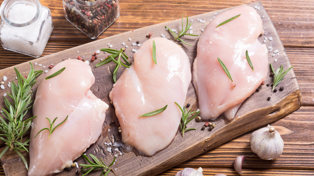 raw boneless chicken breasts on cutting board