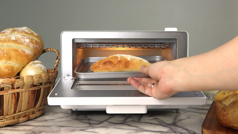 Person putting bread into toaster oven