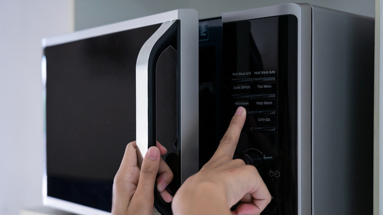Hands closing a microwave 