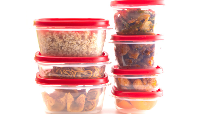 Stacks of clear tupperware with red lids filled with food