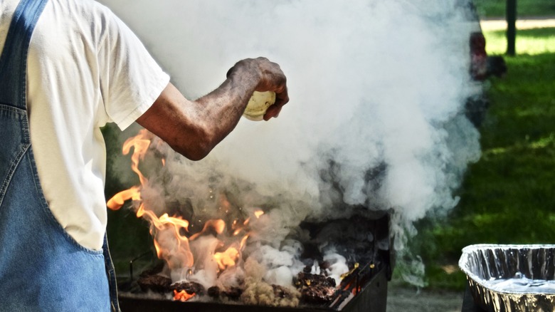 Man dousing BBQ flames