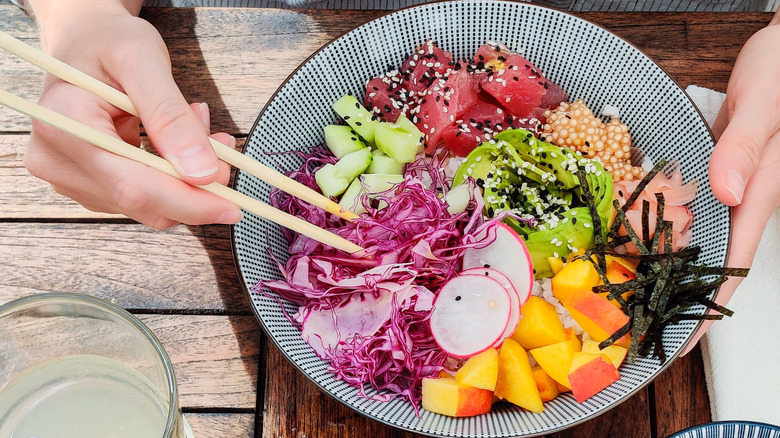 A person using chopsticks to eat poke