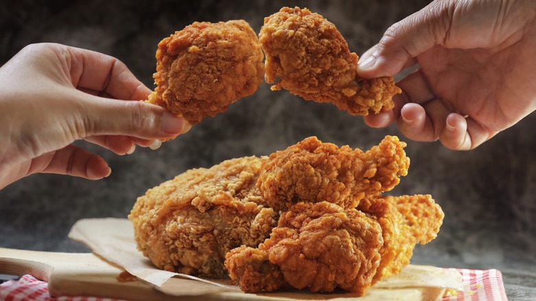 Two hands holding fried chicken