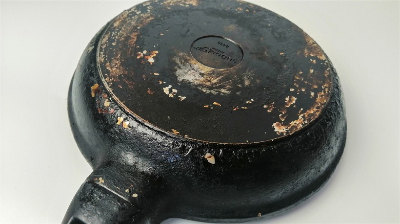 The bottom of a frying pan caked in black buildup.