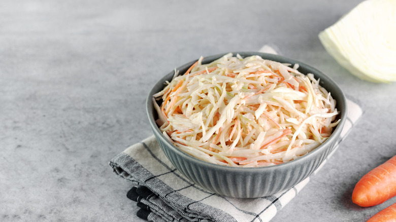 Bowl of coleslaw sitting on top of white checkered dish towel