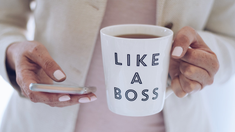 Hand holding white coffee mug with 'Like A Boss' saying