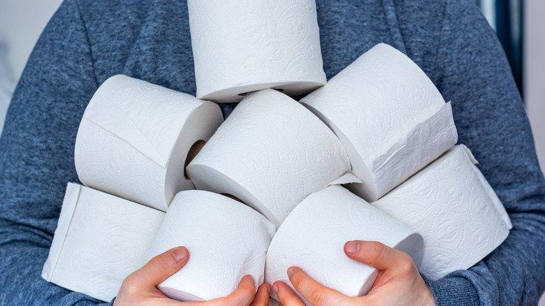 Person carrying several rolls of toilet paper