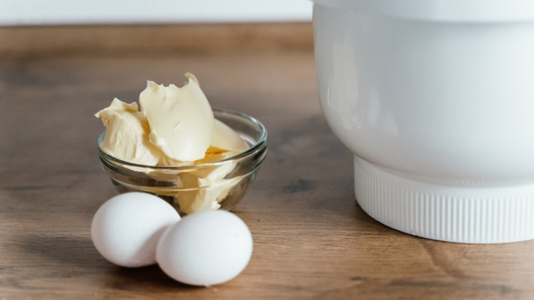 Butter, eggs, and a bowl on a wood table