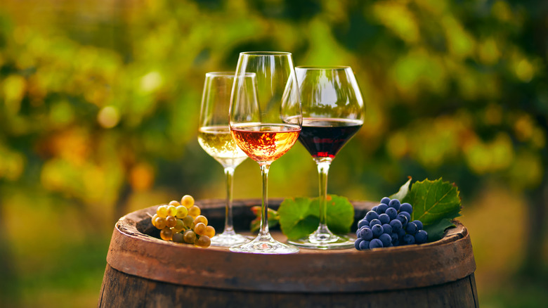glasses of wine on barrel with grapes, vineyard in background
