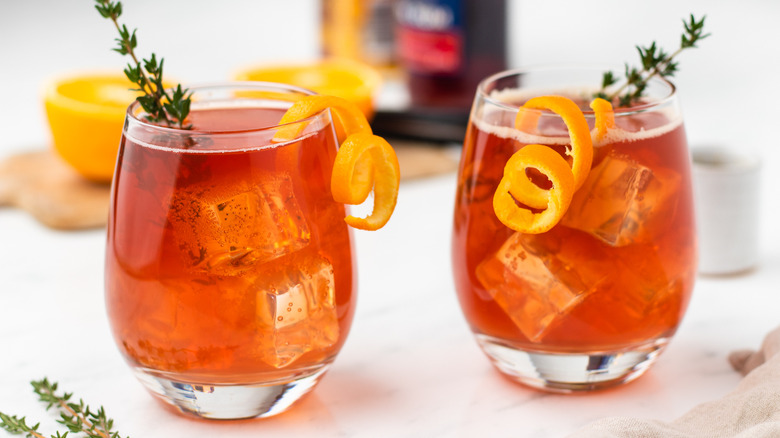 Two cranberry cocktails garnished with orange twists