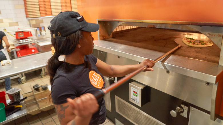 Worker puts pizza in oven at Blaze Pizza