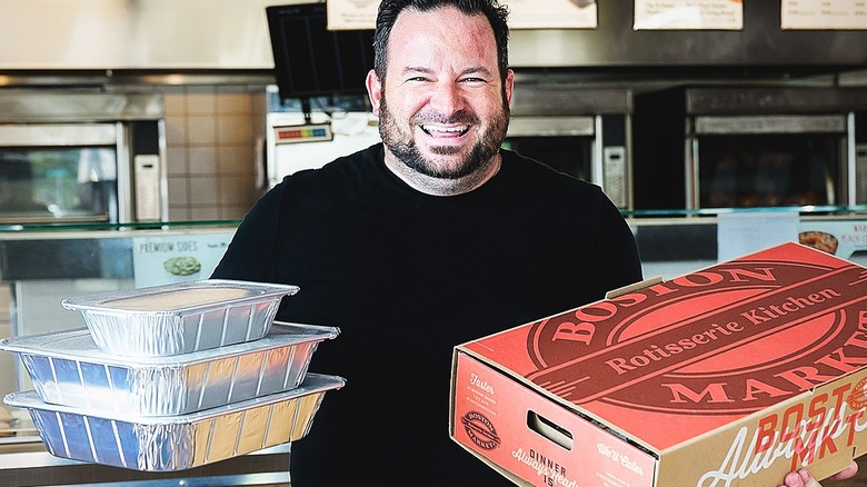 man holding Boston Market boxes