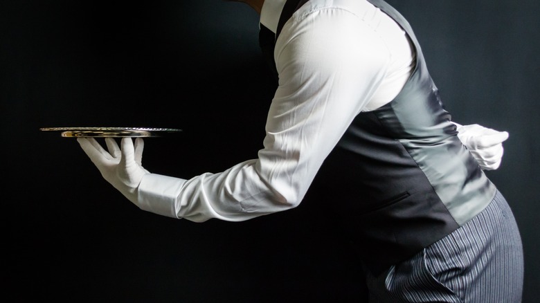 Fine dining waiter holding silver platter at fingertips 