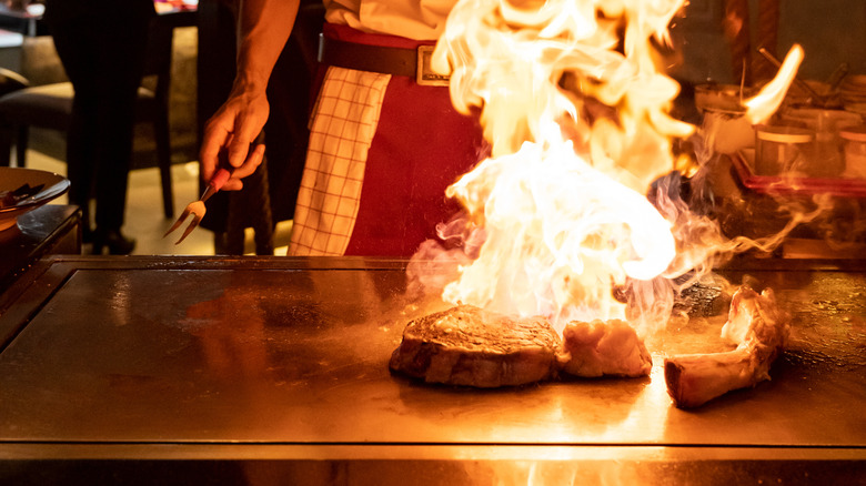Chef cooking steak on a teppanyaki griddle