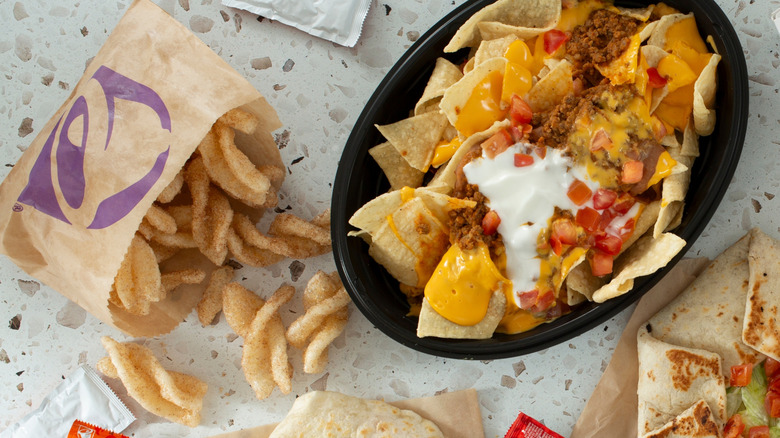 Cinnamon Twists spilling out of their bag and loaded nachos in black oval bowl at Taco Bell.