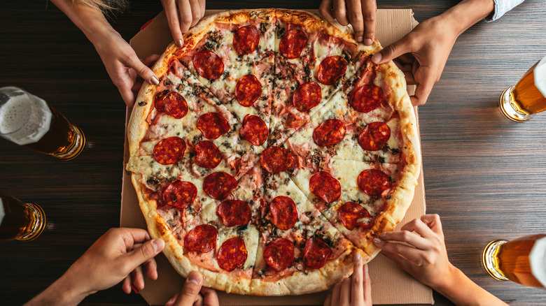 Hands grabbing pizza