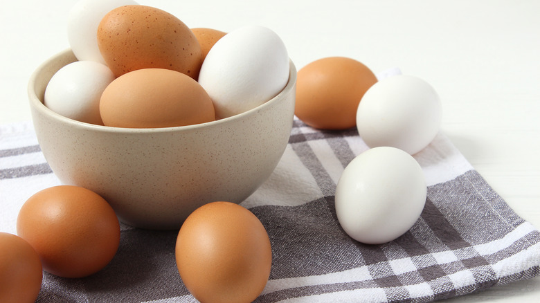 Whole white and brown eggs in bowl