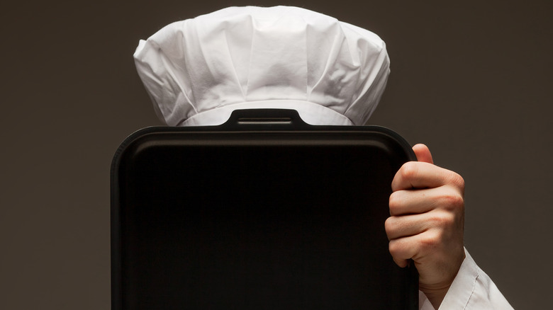 chef hiding behind sheet pan