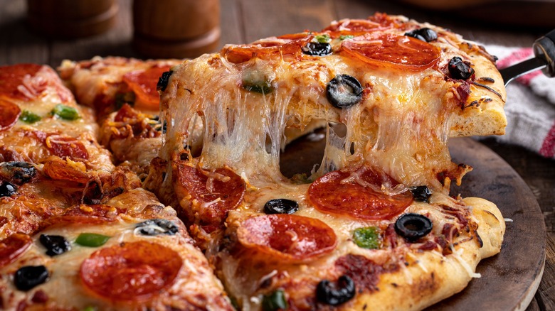 Pizza slice with melted cheese, pepperoni, and olives