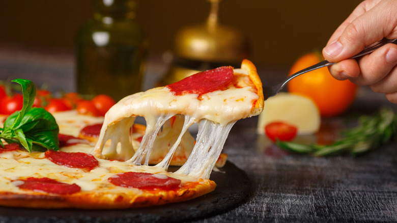 person pulling cheesy pizza slice