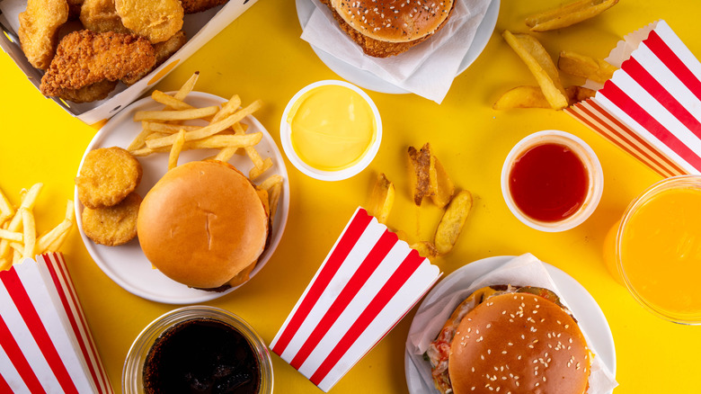 Burgers, nuggets, fries, and sauces on yellow background