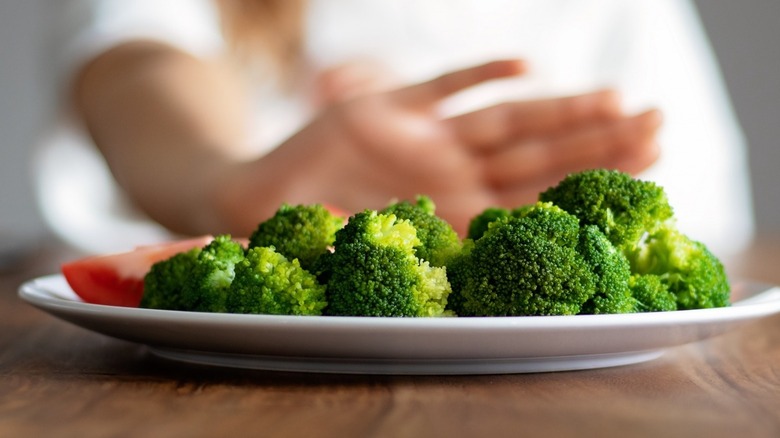 Someone pushing away broccoli 