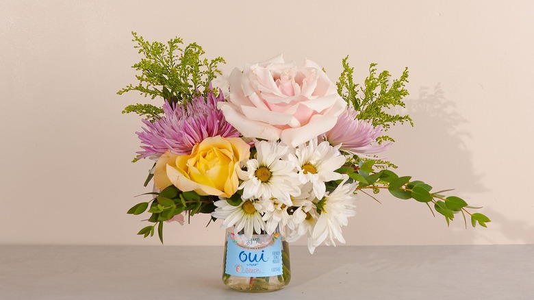 Flowers in a Oui by Yoplait jar on a neutral background
