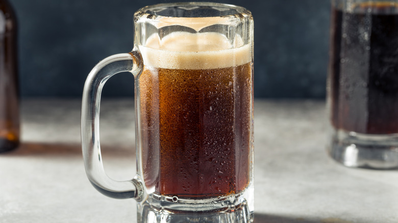 A glass pint glass filled with root beer.