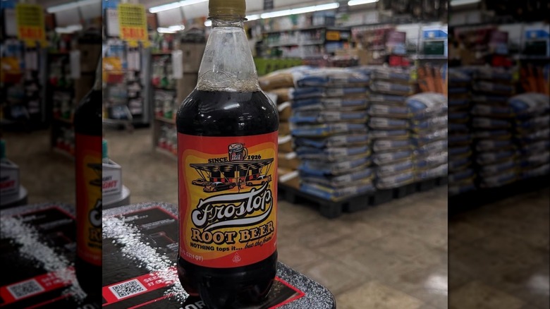 A bottle of Frostop root beer sits on a counter, with hardware supplies in the background.