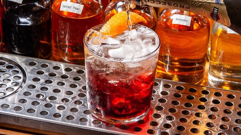 negroni being poured into a tumbler