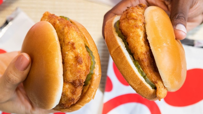 Two people holding Chick-fil-A sandwiches