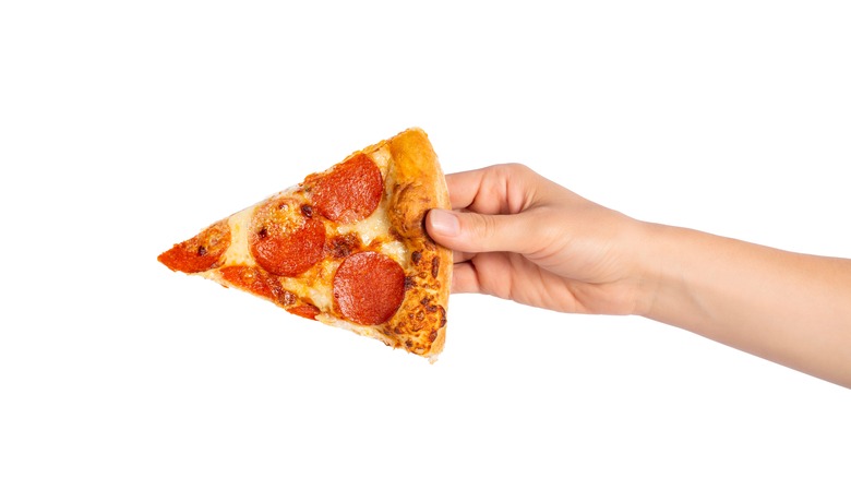 Hand holding pizza slice