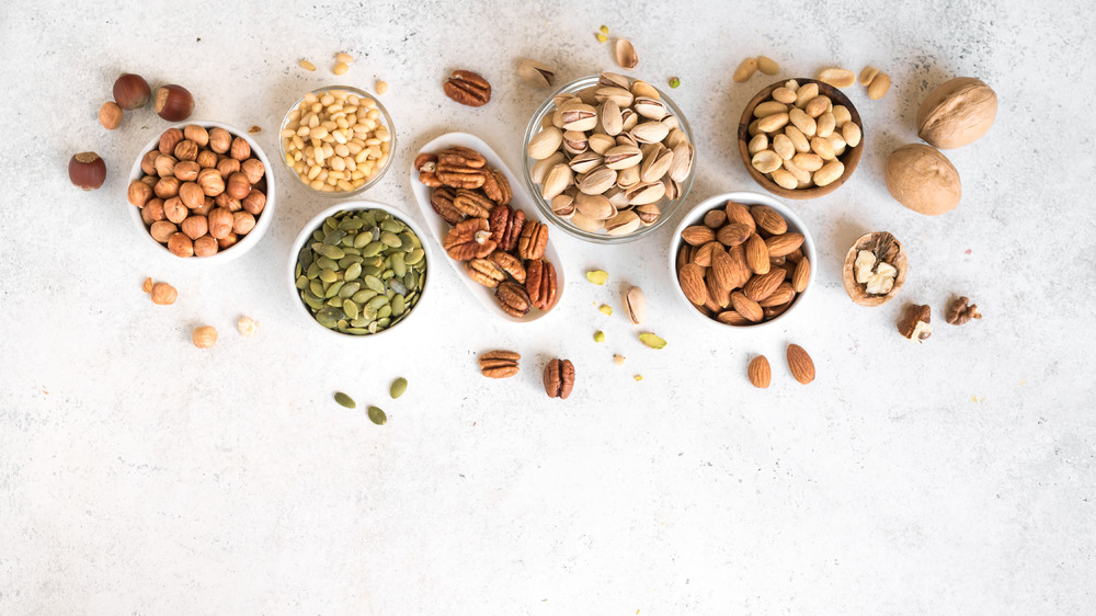 Different kinds of nuts in white bowls