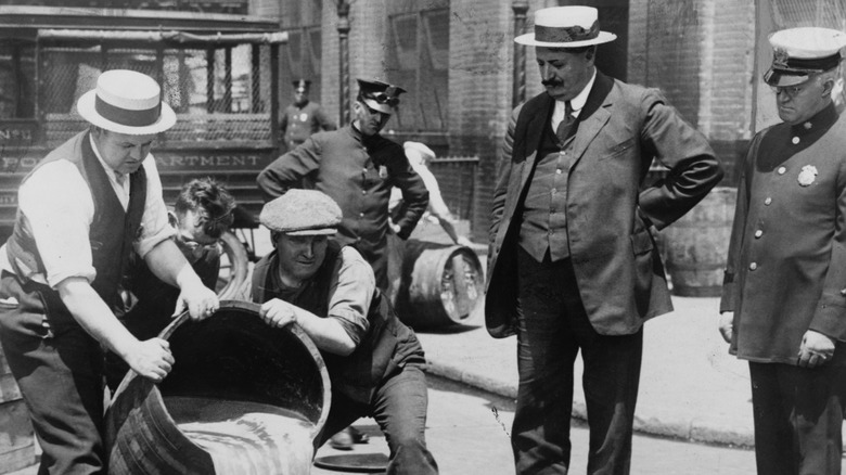 A police commissioner overseeing barrels of alcohol being poured out during Prohibition