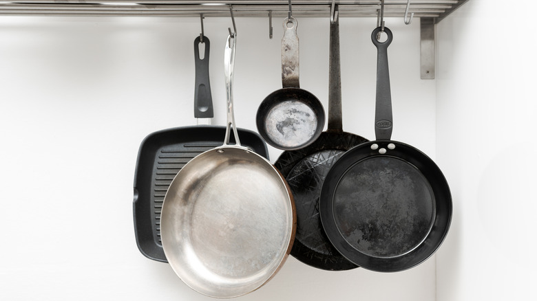 Various pans hanging from rack in white kitchen.