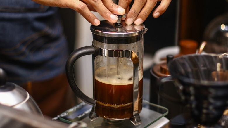 hands plunging french press coffee