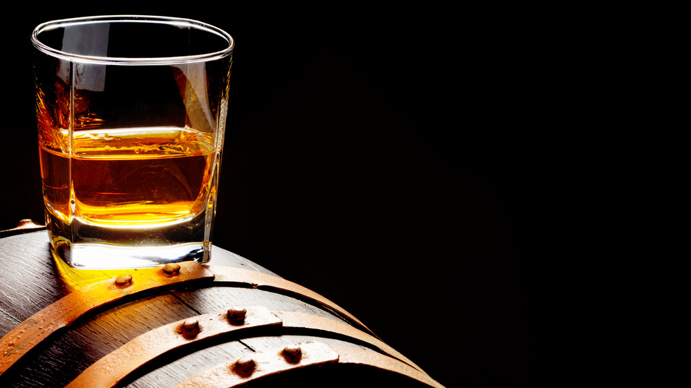 Glass of whiskey setting on top of a barrel