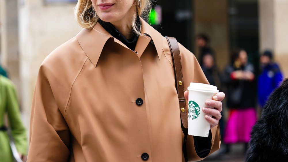 Woman holding cup of Starbuck's coffee