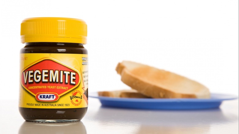 Vegemite container beside bread on plate