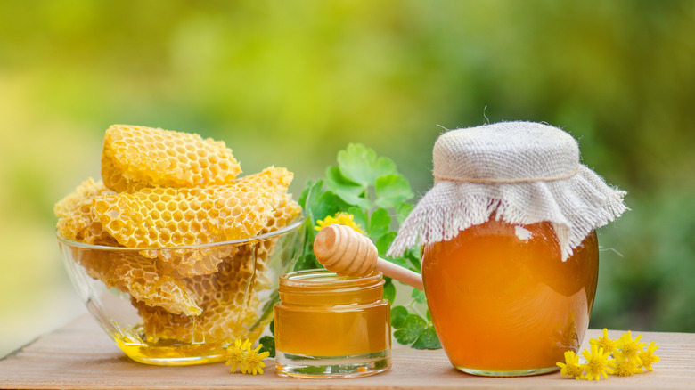 Bowl of honeycombs next to jars of honey