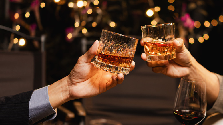 Two people toasting glasses of whiskey