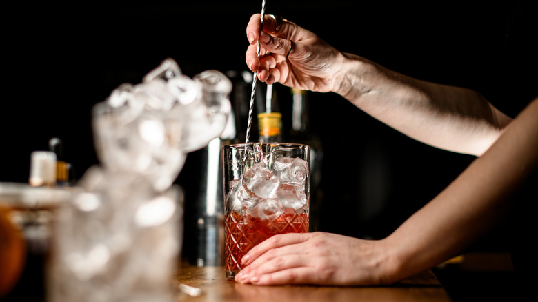 Bartender stirring a whiskey-based cocktail