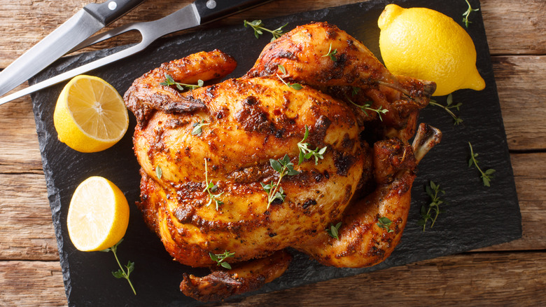 Roast chicken on cutting board with lemons