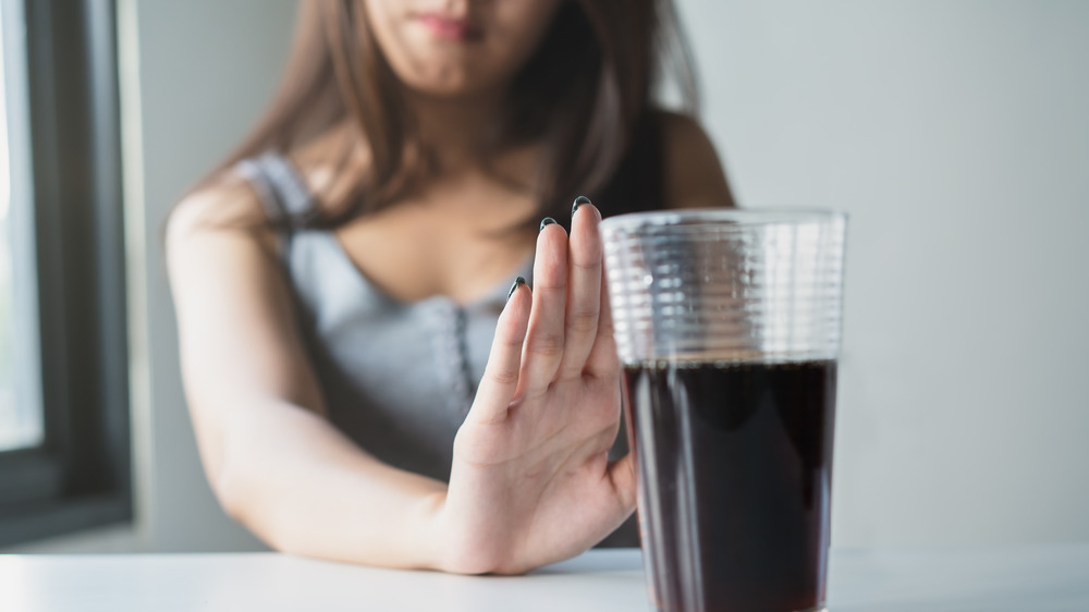 Women with hand up saying no to soda