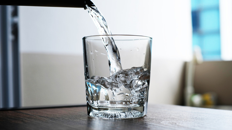 Water being poured into glass jar on wood table