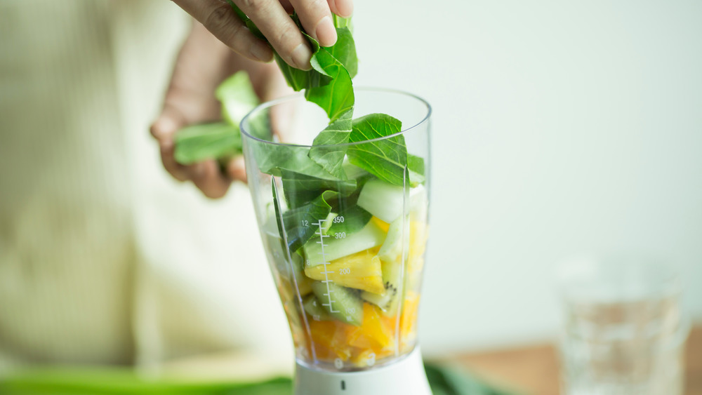 Woman adding smoothie ingredients to a blender