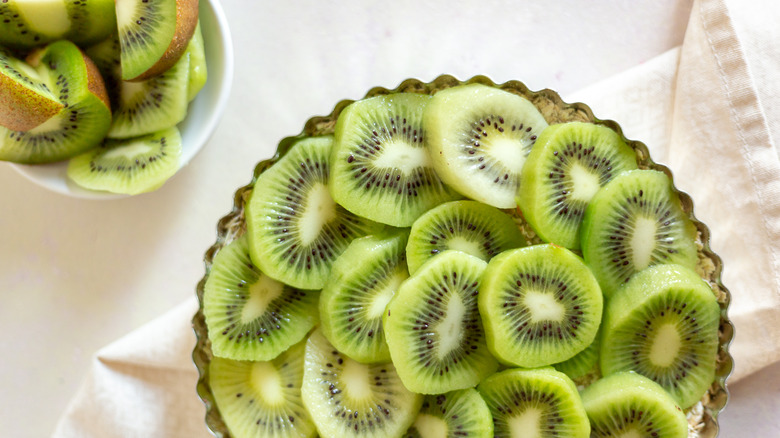 Unbaked kiwi pie on white tablecloth